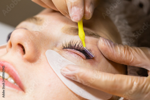 Female face under procedure of eyelashes lamination in beauty salon