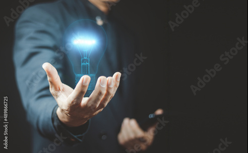 businessman hand holding light bulb with finance document and tool.