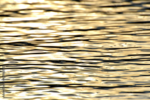 Golden ocean water, photo background. Beautiful summer sea, sunset time. Ocean surface natural background. Backdrop for lettering, cards, banner, design and decor elements. 