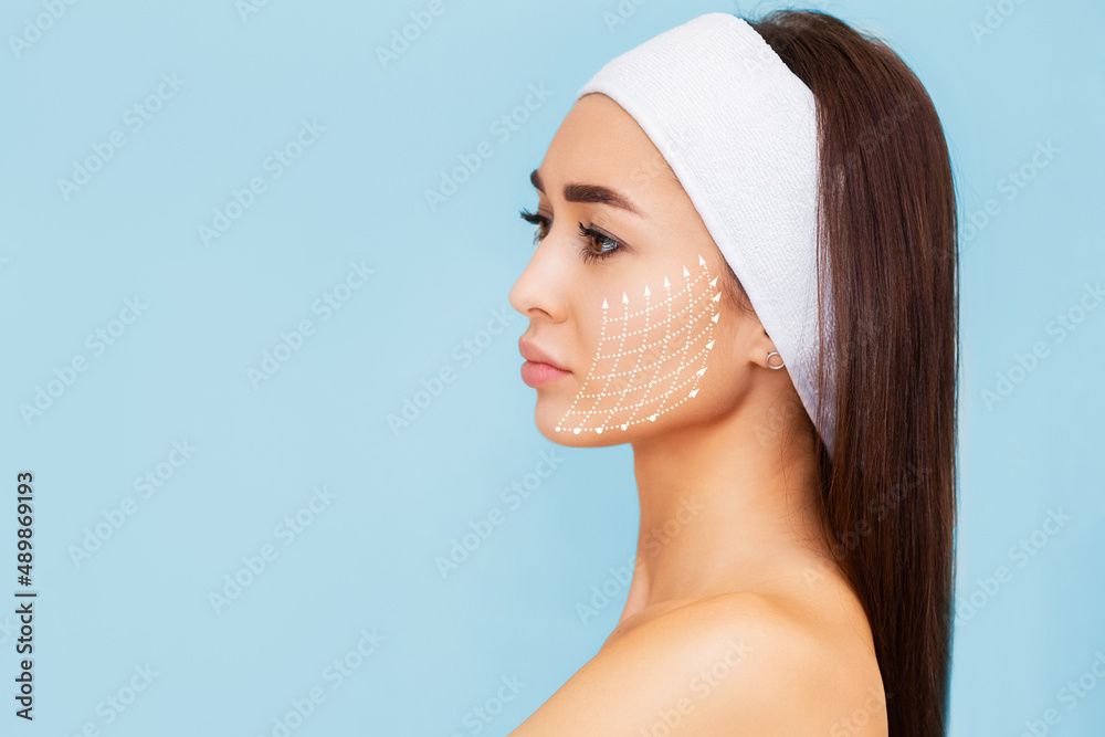 © _KUBE_ - Portrait of a woman with a painted grid on her face. Blue background and copy space. The concept of thread lifting and rejuvenation