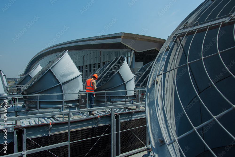 Engineer under checking the industry cooling tower air conditioner is water cooling tower air chiller HVAC of large industrial building to control air system.