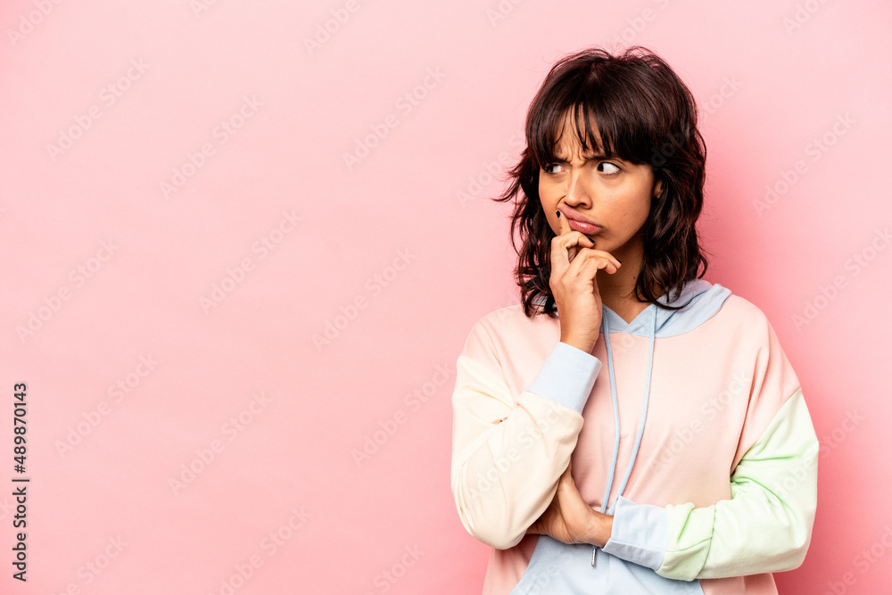 Young hispanic woman isolated on pink background looking sideways with doubtful and skeptical expression. Young hispanic woman isolated on pink background looking sideways with doubtful and skeptical expression.