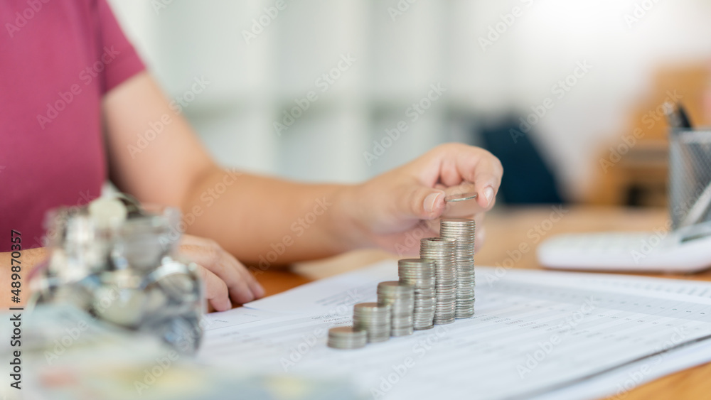 Saving concept the woman piling her coins to make the towers in different heights Saving concept the woman piling her coins to make the towers in different heights