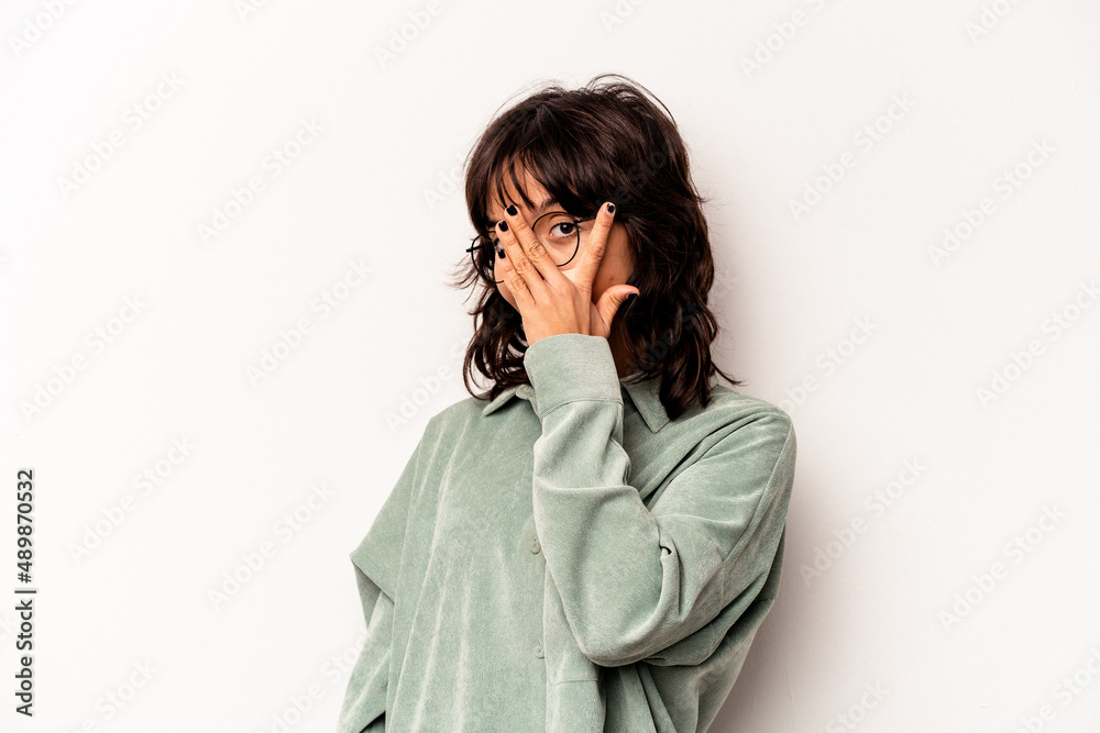 Young hispanic woman isolated on white background blink at the camera through fingers, embarrassed covering face. Young hispanic woman isolated on white background blink at the camera through fingers, embarrassed covering face.