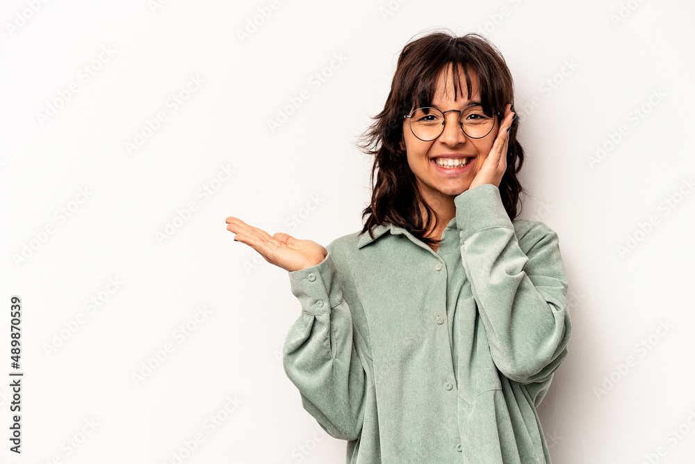 Young hispanic woman isolated on white background holds copy space on a palm, keep hand over cheek. Amazed and delighted. Young hispanic woman isolated on white background holds copy space on a palm, keep hand over cheek. Amazed and delighted.
