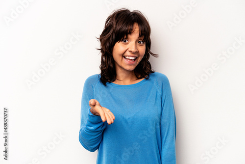 Young hispanic woman isolated on white background stretching hand at camera in greeting gesture.