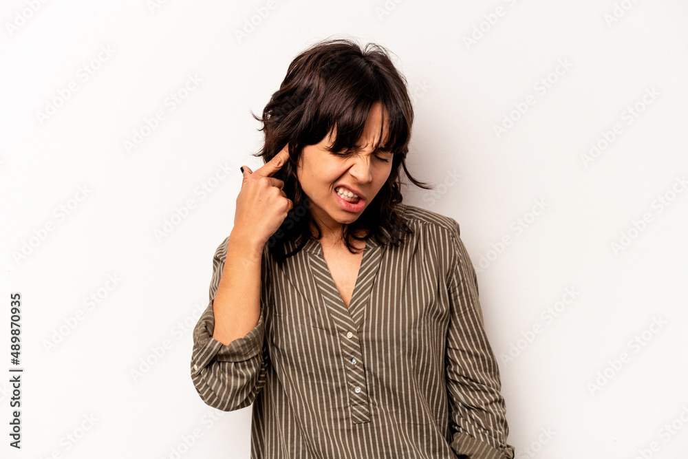 Young hispanic woman isolated on white background covering ears with hands.
