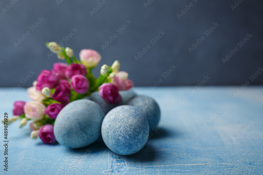 Painted Easter eggs on blue background with purple flowers. Spring holiday, symbolic food. Close up shot, copy space. Painted Easter eggs on blue background with purple flowers. Spring holiday, symbolic food. Close up shot, copy space.