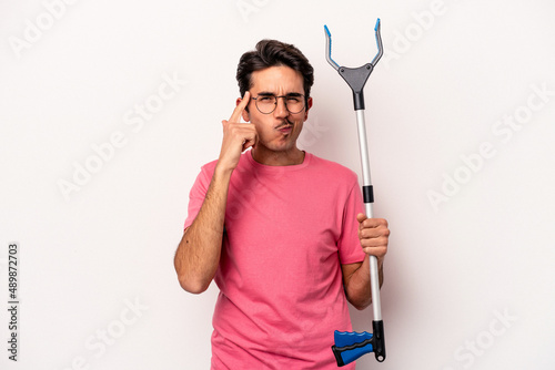 Young caucasian man holding a garbage collector isolated on white background pointing temple with finger, thinking, focused on a task.