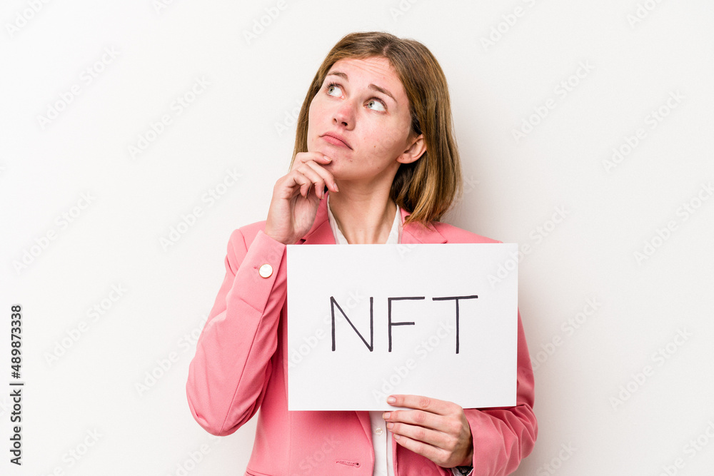 Young English woman holding a NFT placard isolated on white background looking sideways with doubtful and skeptical expression. Young English woman holding a NFT placard isolated on white background looking sideways with doubtful and skeptical expression.