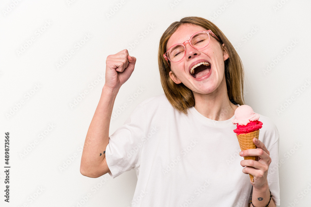 Young English woman holding an ice cream isolated on white background raising fist after a victory, winner concept. Young English woman holding an ice cream isolated on white background raising fist after a victory, winner concept.