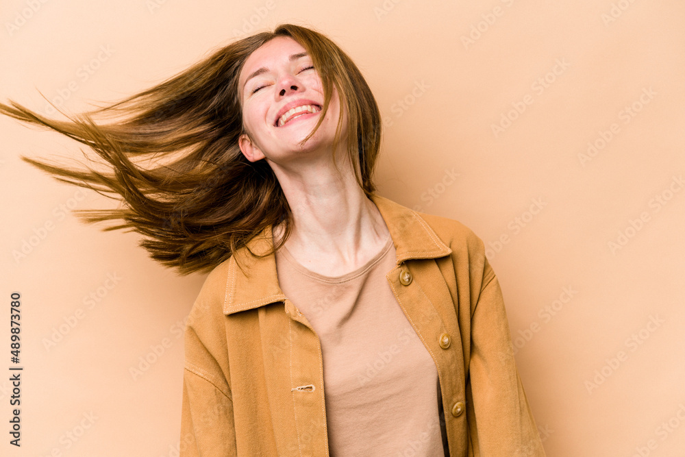 Young English woman isolated on beige background dancing and having fun. Young English woman isolated on beige background dancing and having fun.