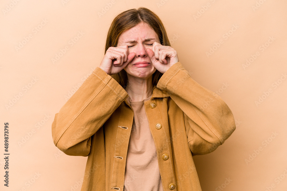 Young English woman isolated on beige background whining and crying disconsolately. Young English woman isolated on beige background whining and crying disconsolately.
