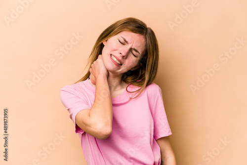 Young English woman isolated on beige background suffering neck pain due to sedentary lifestyle.
