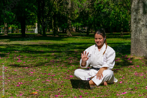 una mujer de arte marciales entrenando karate cinta negra haciendo reunion online en computadora photo