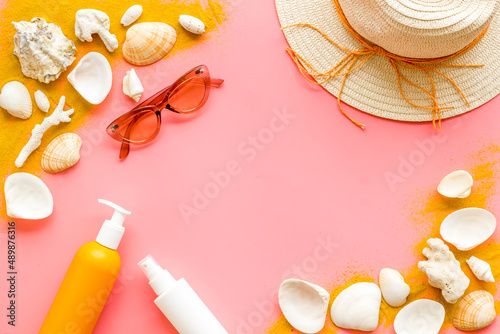 Beach sand and seashells with straw hat and bottles od sunscreen