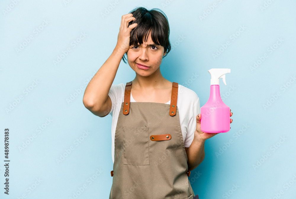 Young hispanic gardener woman holding a hand sprayer isolated on blue background being shocked, she has remembered important meeting. Young hispanic gardener woman holding a hand sprayer isolated on blue background being shocked, she has remembered important meeting.