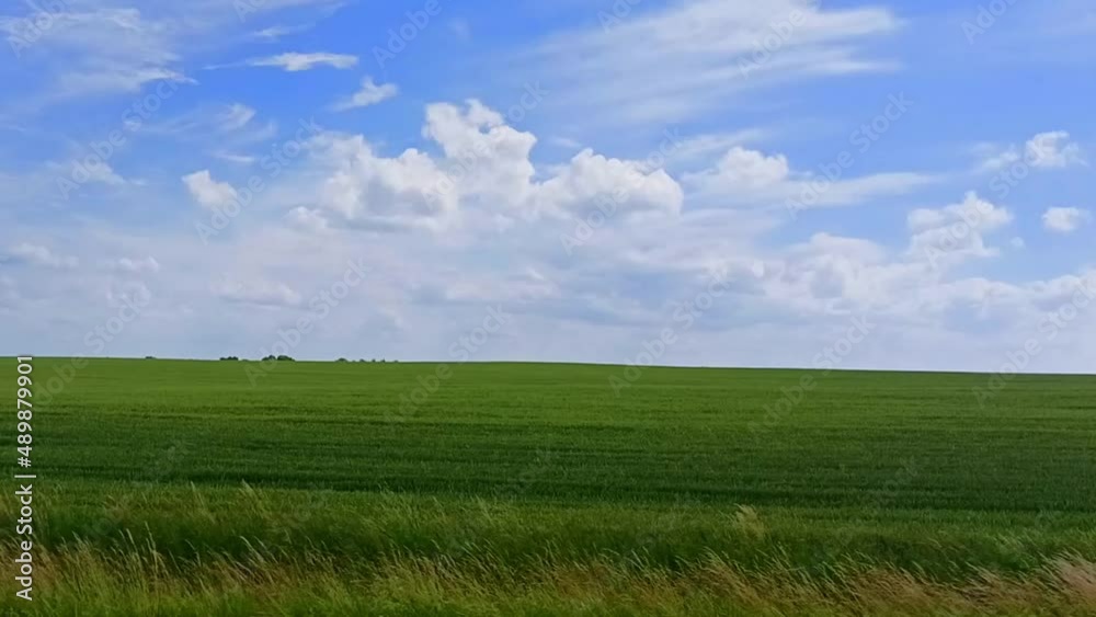 View through side window of a car auto in motion along the green field under a blue sky in summer. Tourism and travel, journey trip themed fotage. Beautiful nature and landscape. View through side window of a car auto in motion along the green field under a blue sky in summer. Tourism and travel, journey trip themed fotage. Beautiful nature and landscape.