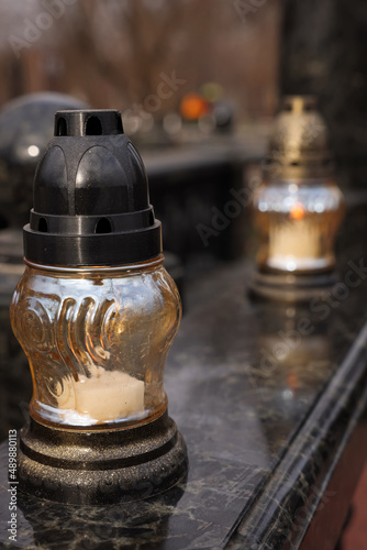 Grave lantern with candle on granite surface at cemetery