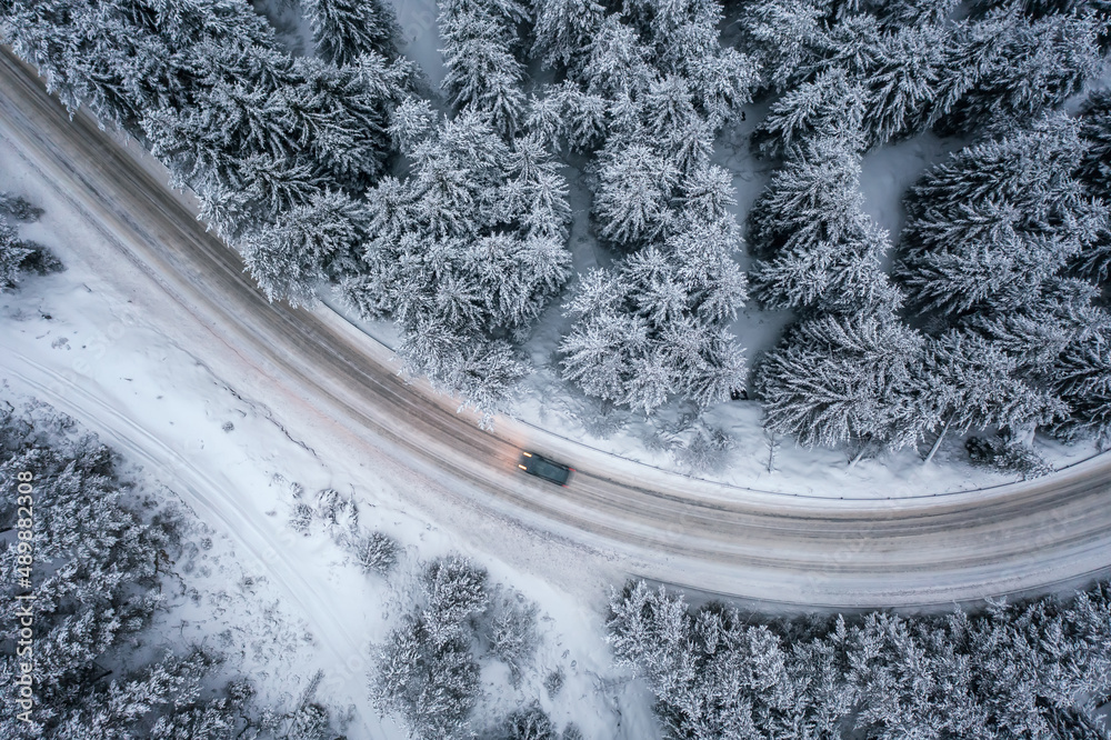 Aerial drone photography of a picturesque snowy forest with a car on a ...