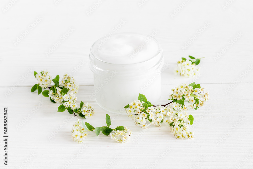 White moisturizing cream cosmetic for spa treatment with blossoms flowers White moisturizing cream cosmetic for spa treatment with blossoms flowers