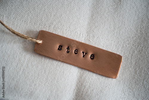 First name Steve identity engraved name dog tag copper metal name plate badge. Shiny and clean stamped letters on retro trinket pendent. Short for Steven or Stephen.