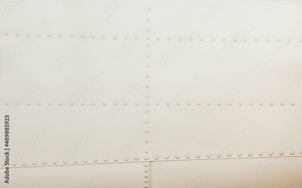Silver metal surface of the aircraft fuselage with rivets. Fuselage detail view. Airplane metallic fuselage detail with rivets. Silver metal surface of the aircraft fuselage with rivets. Fuselage detail view. Airplane metallic fuselage detail with rivets.