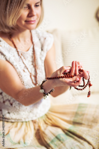 Woman at meditate place in lotus position using Mudra,  hand close up, strands of  beads used for keeping count during mantra meditations