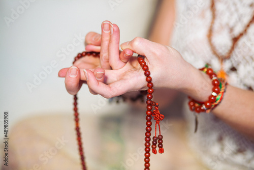 Woman at meditate place in lotus position using Mudra,  hand close up, strands of  beads used for keeping count during mantra meditations