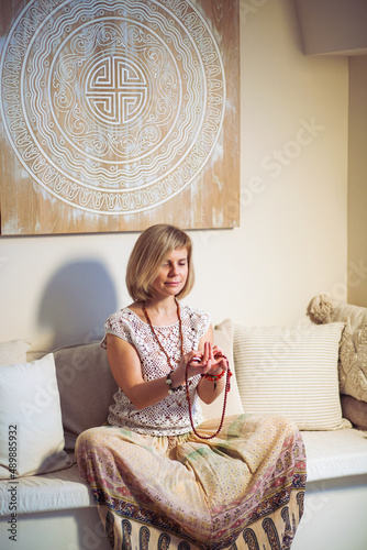 The concept of zen, peace, balance. A woman sits on a sofa and meditates  using Mudra, keeping her eyes closed and legs crossed