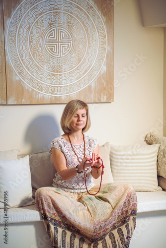 The concept of zen, peace, balance. A woman sits on a sofa and meditates  using Mudra, keeping her eyes closed and legs crossed