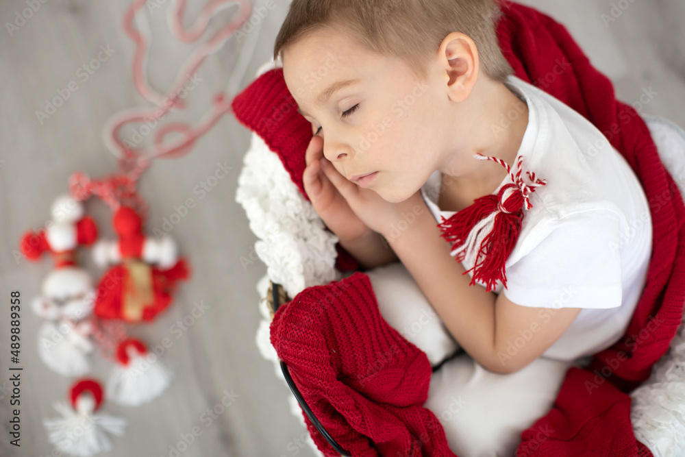 Cute child, blond boy, playing with white and red bracelet, martenitsa