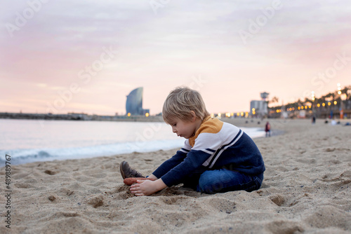 Cute little child, toddler boy, playing on the beach in Barcelona city, family travel with kids