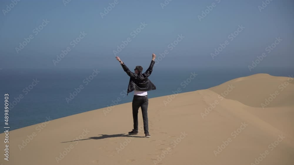 A young man walks along sandy dunes on the seashore. Sandwich Harbour in Namibia A young man walks along sandy dunes on the seashore. Sandwich Harbour in Namibia