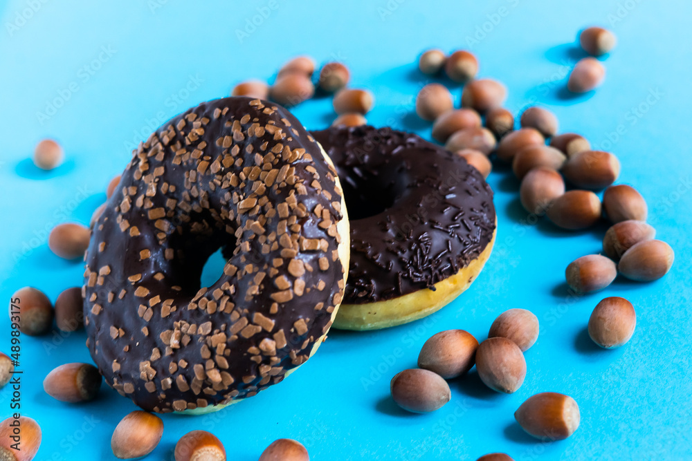 Donut with hazelnuts on blue background, close up