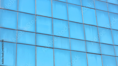 building's glass windows facade background, old building. abstract architectural background. reflection of the clear blue sky on windows. detail of glass building background .