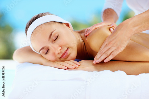 Relaxed young lady receiving shoulder massage from a masseuse. Relaxed young woman receiving shoulder massage from a professional masseuse.