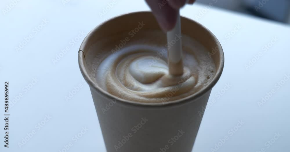 Mixing coffee latte with paper straw
