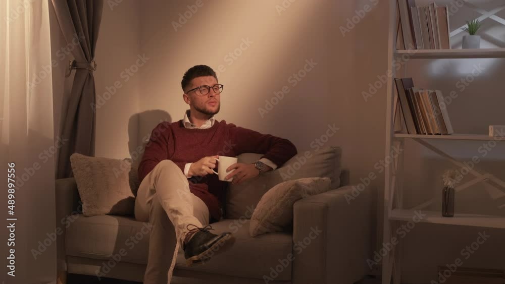 Coffee break. Elegant man. Successful lifestyle. Relaxed smart casual guy enjoying hot beverage sitting comfortable sofa in dark light room interior. Coffee break. Elegant man. Successful lifestyle. Relaxed smart casual guy enjoying hot beverage sitting comfortable sofa in dark light room interior.