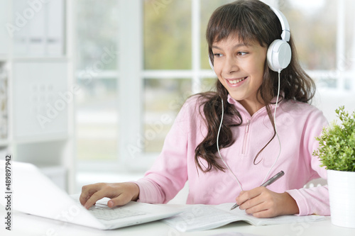 Portrait of little girl using laptop while studying at desk