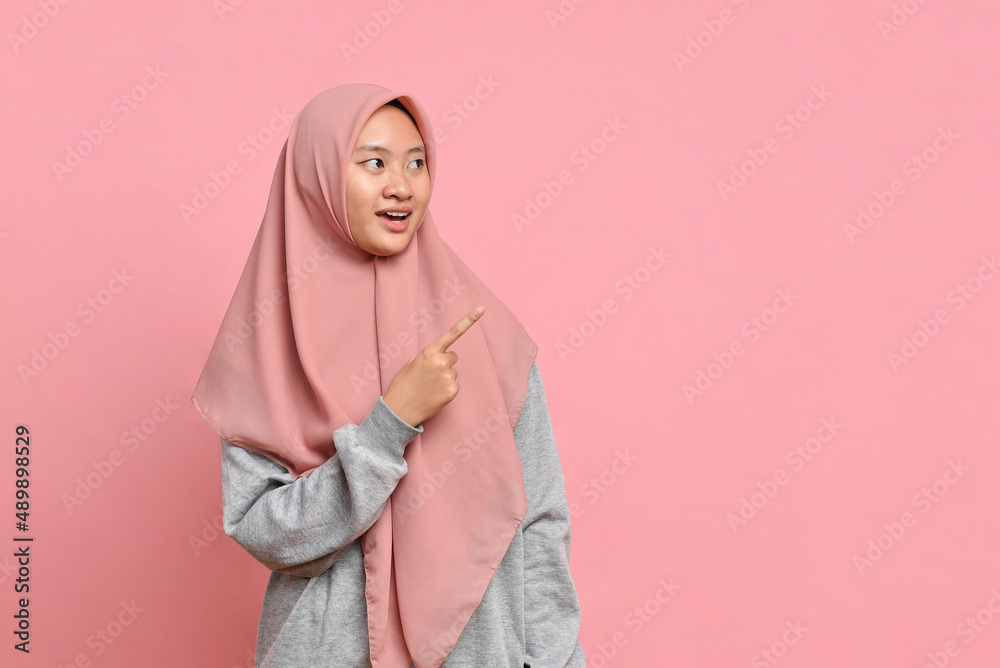 Fototapeta premium Young Asian muslim woman points a copy space