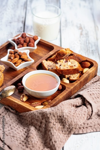 Homemade italian biscotti or cantuccini with almonds and dried fruits on white wooden background. Cookies and milk, honey and nuts. Traditional Italian cookies. Selective focus. Copy space