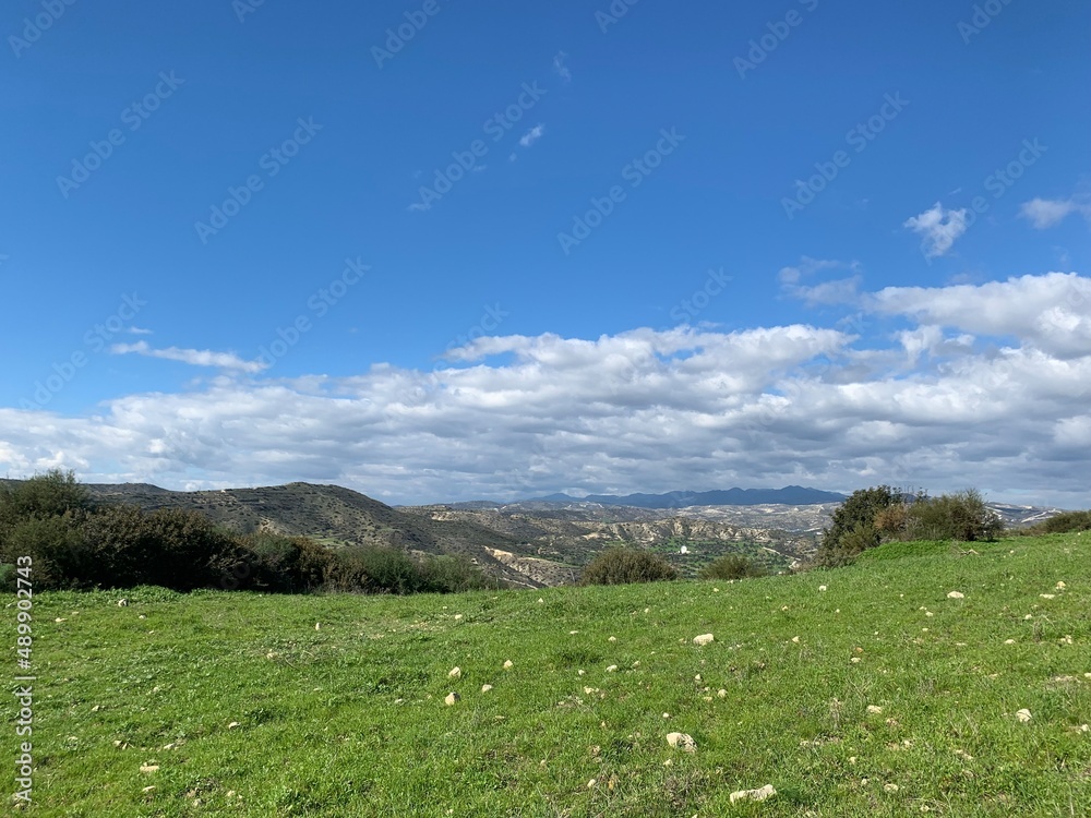 green valley in mountains, blue sky with white clouds