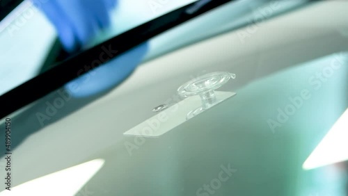 technican placing a mirror below an stone chip before fixing the car glass photo