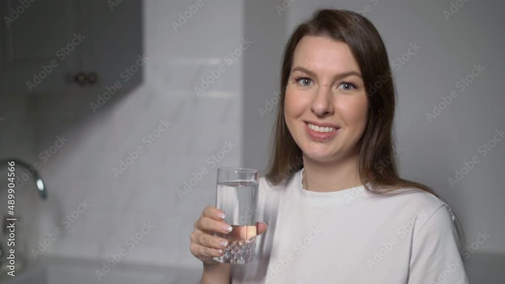 A young woman is holding a glass of clean water. The girl drinks water. A young woman is holding a glass of clean water. The girl drinks water.