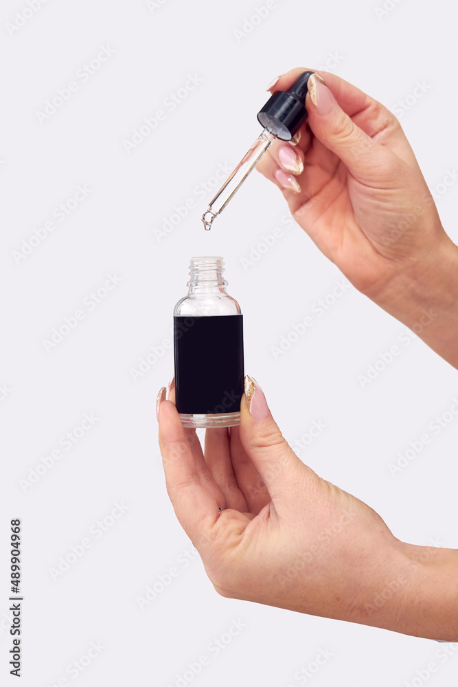 Close Up Studio Shot Of Woman Holding Bottle Of Essential Or Cannabis Oil With Dropper Close Up Studio Shot Of Woman Holding Bottle Of Essential Or Cannabis Oil With Dropper