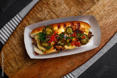 hot dog with jalapeno and vegetables on a dark background