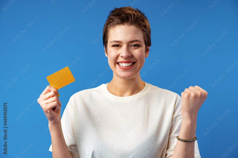 Image of young woman holding business card with copy space on blue background Image of young woman holding business card with copy space on blue background