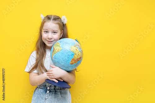 little girl on a yellow background hugs a globe with emotions overwhelming her © Елена Белоусова
