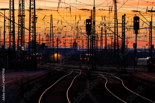 Sunset panorama with colorufl sky and warm atmosphere at Dortmund main station Germany. Railway tracks, signals, catenary and high voltage overhead lines with reflections of sunlight. Public transport